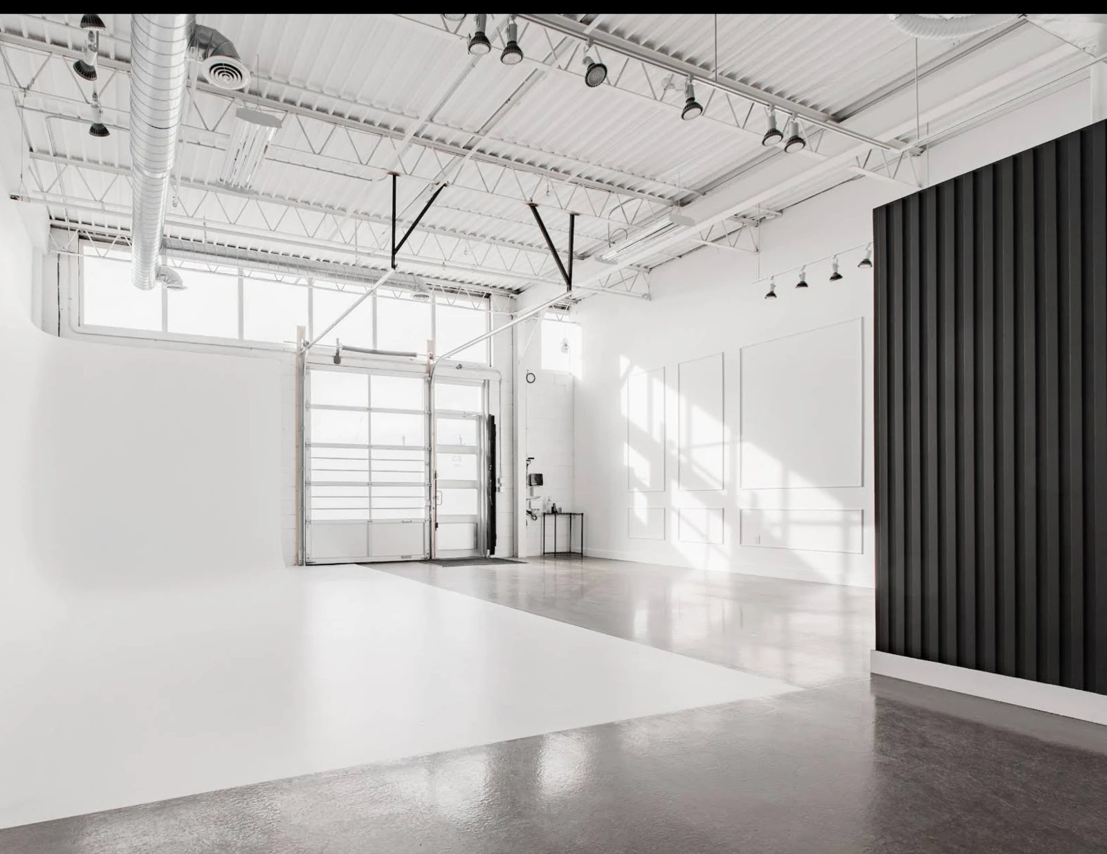 Photography studio build-out with large white cyclorama, wainscotting wall and black wood slat accent wall